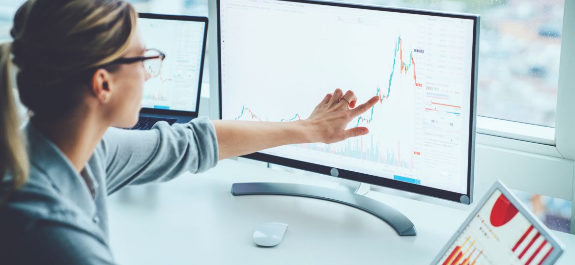 Business woman study financial market to calculate possible risks and profits.Female economist accounting money with statistics graphs pointing on screen of computer at desktop. Quotations on exchange